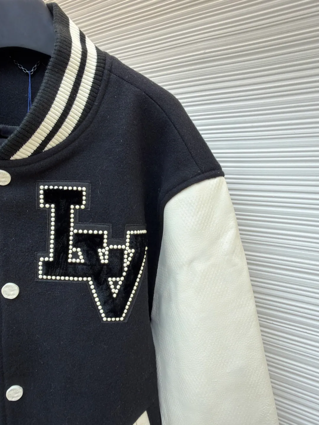 LOUIS VUITTON checkerboard embossed genuine leather and wool baseball jersey ●Original version: 51000 purchased and developed ●Item number: 1680926-i15 ●Fabric: genuine leather wool fabric ●Technology: embroidery ●Version: fitted version ●Weight: about 1770 grams ●Size: 44-46-48-50 ●Description: The fabric is made of 80% wool, with a weight of 750g. It is made of newly sheared wool and is dyed in reactive black in the vat. The colored cloth is bristle process. After brushing 5 times and washing 6 times, the fluffy surface fluff is trimmed flat, and the surface of the fabric appears fluffy. It has a hollow three-dimensional fluffy effect. You can feel the elasticity of the fabric when you touch and press it with your hands. The newly sheared wool yarn is long-fiber and is not easy to pill after shearing. The front and back panels are embroidered with Tajima embroidery machines imported from Japan. The nylon material is super matte and the tatami stitch method is multi-layered. Overlapping thread embroidery, the front chapter is made of viscose yarn, three-dimensional toothbrush embroidery, the mold is opened to determine the pile height and the suede is smoothed by hand, using acrylic round bubble beads, the surface of the bubble beads is sprayed three times, the base paint is latex paint, and the middle layer is sprayed with pearls Pearl white paint, the outer layer is sprayed with translucent glossy paint, the translucent bright white effect is completely comparable to that of mother-of-pearl. There are a total of 154 beads in the chapter. Each bead is dusted and positioned to ensure that it is flush with the edge of the chapter. The visual effect is not obtrusive. The two sleeves are made of water Made of dyed cowhide. Compared with spray-painted cowhide, there is nothing attached to the surface of water-dyed cowhide. Pure water-based dyes are continuously stirred in the tank to naturally color. During the period, samples are taken to compare the color of the Y-version sleeves according to the degree of coloring. When the colors are basically the same, they can be washed and dried naturally to produce the finished product. The thickness of the finished leather is 12mm. The embossing is made of a large-size aviation aluminum plate material mold. All the flowers are pressed according to the code positioning. An electric hydraulic control system is used, and the constant temperature and timing are automatically operated. The small sleeve logo is embossed separately from the small mold. It is pressed by electromagnetic pulse pressure and heating. After the sleeves are cut and embossed, the leather base is all shoveled to a thickness of 8mm. The leather thickness is reduced and the hand feels softer and closer to the body. The diamond-shaped plaid embossing on the surface causes an anti-skin phenomenon due to the thinning of the leather base. The pattern will naturally increase from the deep base state. Lightened, the diamond check pattern and the leather pebbles form a visually invisible effect. It is matched with cupro + cotton blended lining, the ribs are made of combed cotton yarn, and the horizontal loom imported from Taiwan has inter-color jacquard. It is matched with a custom-made molded aluminum alloy material with a logo spray-painted four-button buckle.